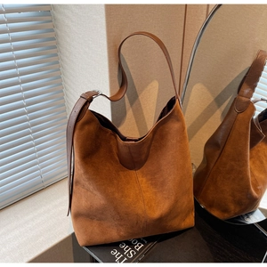 Detail of vintage brown suede hobo bag featuring adjustable leather strap and fine stitching