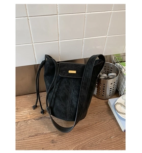 Dettaglio di una borsa a secchiello in camoscio nero con elegante fibbia in metallo oro