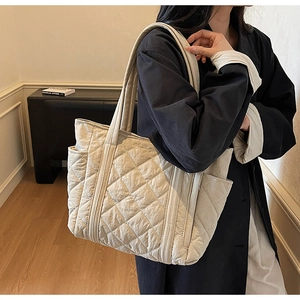 Detail of beige quilted tote bag showing rhombus stitching and convenient side pocket