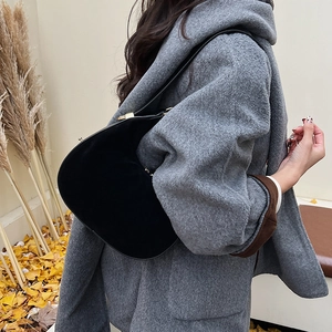 Detail of black suede hobo bag featuring gold hardware and adjustable strap studs