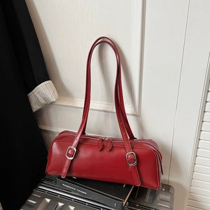 Detailed close-up of a red rectangular leather handbag with dual zippers and silver buckles