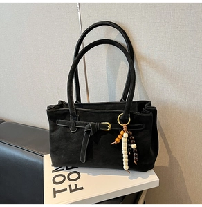Detailed close-up of a black frosted bucket bag with a stylish beaded charm and metal buckle