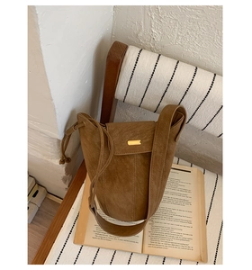 Dettaglio borsa a secchiello marrone vintage con fibbia in metallo dorato su sedia in legno