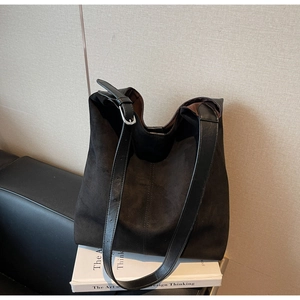 Close-up of vintage suede bucket bag with adjustable leather strap on art books