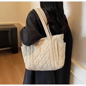 Détail du sac cabas matelassé beige montrant les poches latérales et les doubles anses