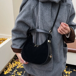 Detail of black matte and smooth leather hobo bag with gold zippers in autumn setting