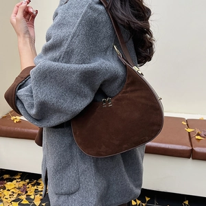 Detailed macro view of dark brown suede crescent shoulder bag with golden zipper hardware