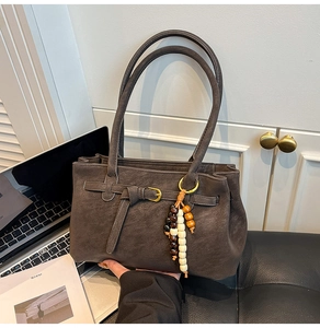 Close-up of vintage brown bucket bag with belt buckle detail and retro wooden bead charm