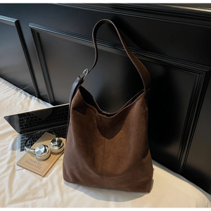 Detail of dark brown suede bucket bag with leather strap and silver metal buckle