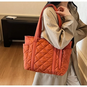Détail du grand sac cabas matelassé orange avec motif de losanges porté par un mannequin