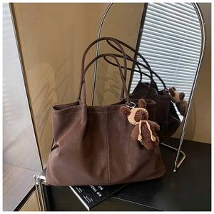Detail of dark brown tote bag with pleated leather texture and a cute bear charm