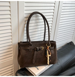 Detail of vintage brown bucket bag with buckle strap and bohemian beaded tassel