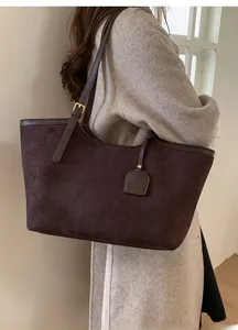 Sac fourre-tout en daim marron foncé porté épaule avec bandoulière et boucle dorée