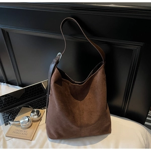 Detail view of large dark brown suede bucket bag with adjustable strap and vintage props