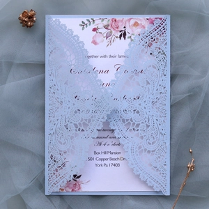 Detail of light blue laser-cut wedding invitation with pink floral inner card on lace mesh