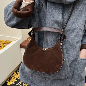 Detail of dark brown suede crescent bag featuring golden zipper and smooth leather strap