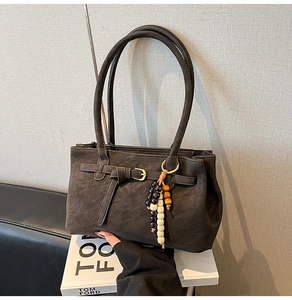 Detail of dark brown matte bucket bag featuring unique multi-color beaded tassel decor