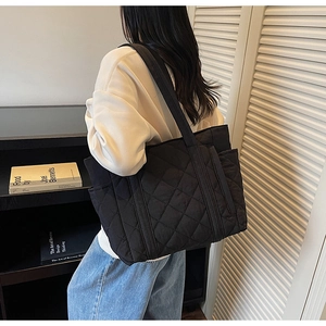 Détail du sac fourre-tout matelassé noir avec poche latérale et large bandoulière renforcée