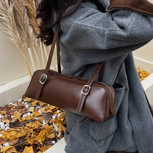 Detail of vintage dark brown baguette bag with dual buckle straps on a gray coat