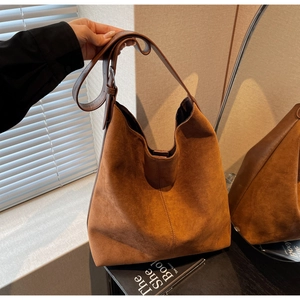 Macro shot of caramel suede hobo bag texture and wide shoulder strap detail