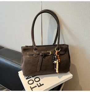Detail of dark brown matte shoulder bag with a buckle and colorful wooden bead tassel