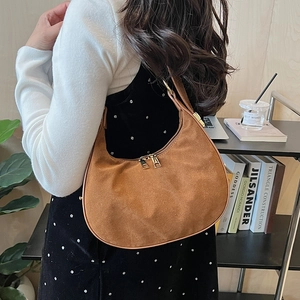 Close-up of brown suede hobo bag with gold zippers and adjustable strap for women