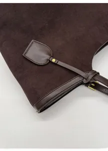 Détail du sac cabas en daim marron foncé avec boucle vintage et bordure en cuir lisse