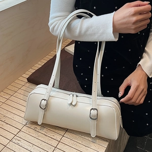 Detail of white cylindrical shoulder bag featuring matte leather and silver buckle strap
