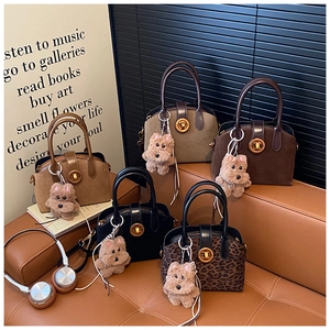 Detail view of premium shell-shaped handbags in five colors with cute plush puppy charms