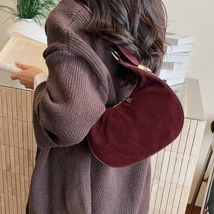 Detail view of burgundy suede crescent bag on shoulder with vintage aesthetic