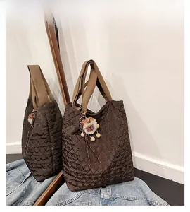 Vista dettagliata della borsa tote trapuntata marrone scuro con ciondolo a forma di orso