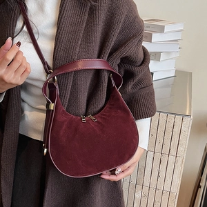 Detail of luxury burgundy suede crescent bag with dual zippers and smooth leather trim