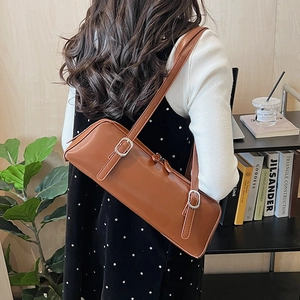 Rear view of brown minimalist leather shoulder bag featuring dual silver adjustable buckles