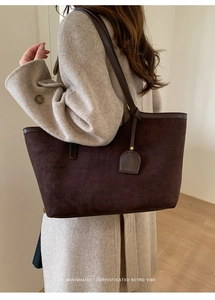 Sac fourre-tout rétro en daim marron foncé porté par un mannequin en manteau de laine
