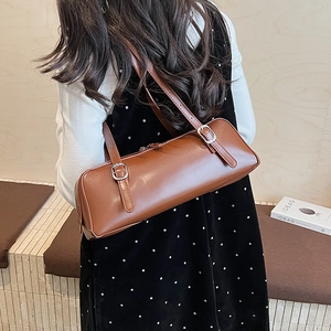 Detailed side view of a brown vintage leather underarm bag on a model shoulder