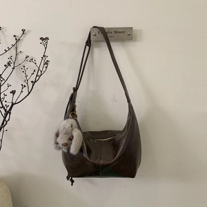 Detail of dark brown glossy leather hobo bag with a cute plush rabbit pendant charm