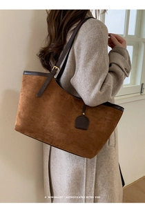 Brown faux suede tote bag with leather strap and golden buckle detail shown on model