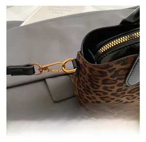 Detailed close-up of leopard print handbag featuring gold metal hooks and black leather strap