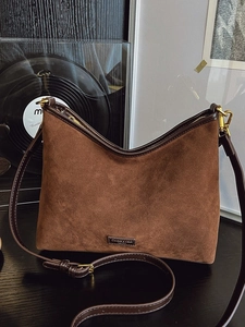 Borsa a secchiello hobo in pelle scamosciata marrone con tracolla su fondo vintage