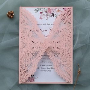 Close-up of laser-cut lace wedding invitation with floral printed inner card