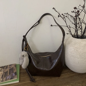 Detail view of deep chocolate oil wax leather Hobo bag with a cute plush rabbit pendant