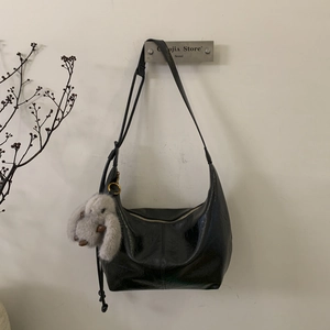 Detail of a black crescent shoulder bag featuring ruched leather and a cute rabbit charm
