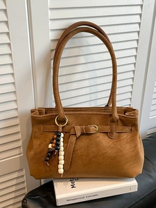 French retro caramel bucket bag with beaded charm and buckle detail on white books