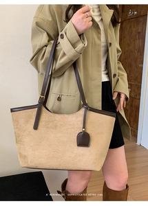 Detailed view of the khaki suede texture and brown leather trim on a retro tote bag