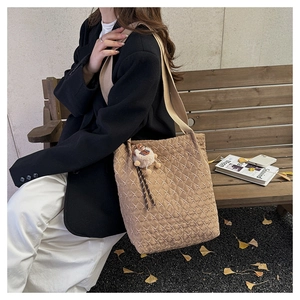 Close-up of quilted tote bag with cute plush bear charm on wooden park bench