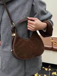 Brown suede hobo handbag with shoulder strap carried by model in a grey winter coat