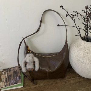 Close-up of brown hobo bag in vintage oil wax leather with cute plush bunny keychain