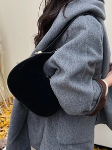 Minimalist black crescent shoulder bag with golden hardware shown in a street style view