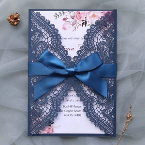 Detailed laser-cut navy wedding invitation with elegant silk bow and floral pattern