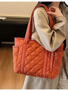Grand sac cabas matelassé orange avec motif à losanges porté par un mannequin